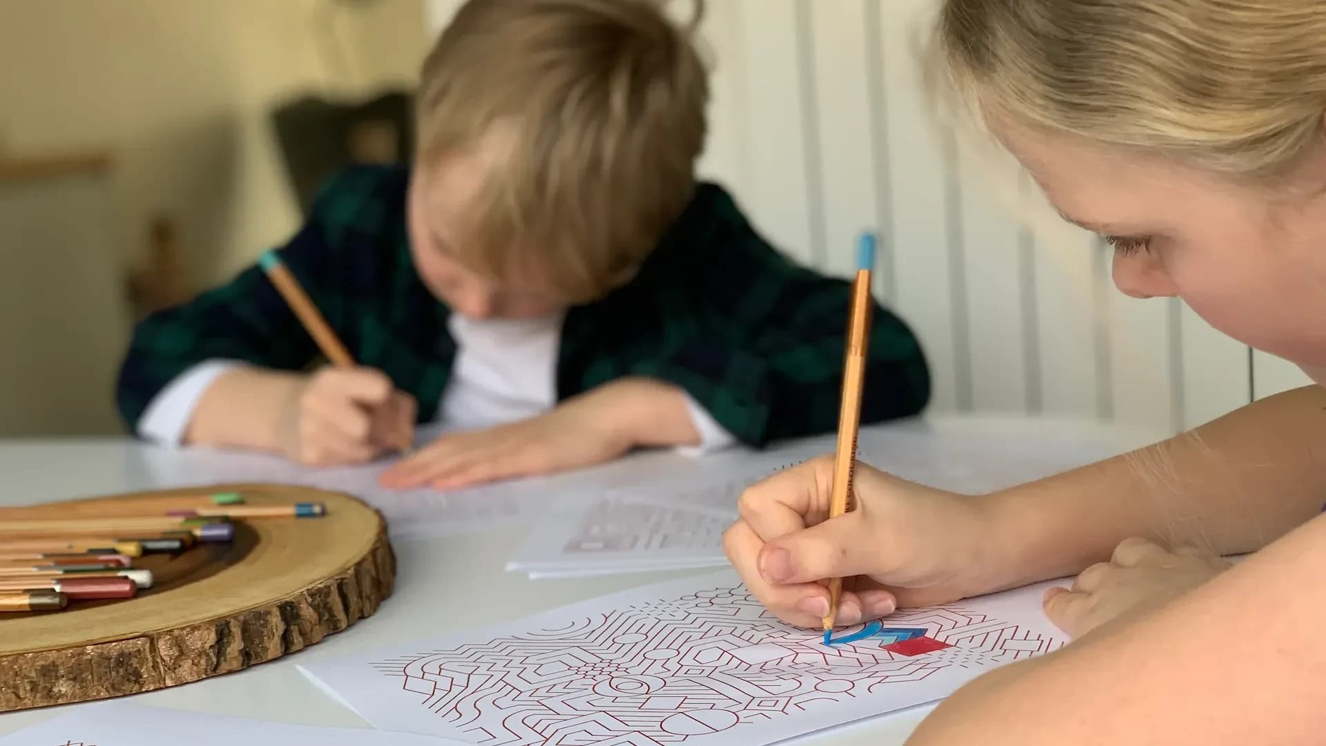 Children colouring printed Infinite Coloring Book patterns at a table